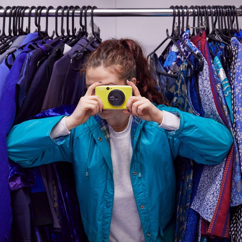 Canon Zoemini C Instant Camera Colour Photo Printer, Bumblebee Yellow Women clicking photo and a closet behind