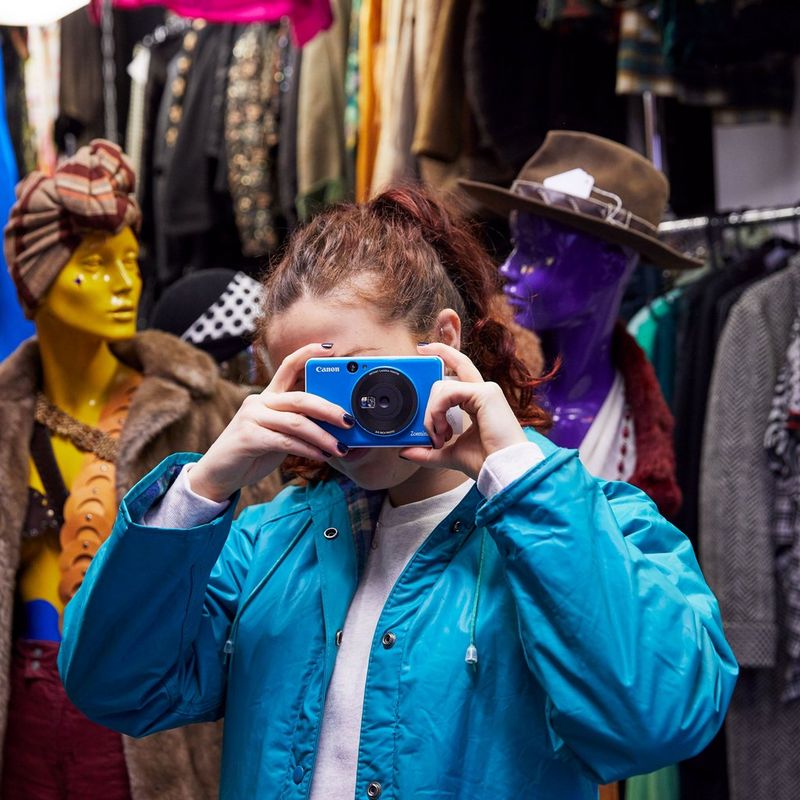 Appareil photo instantané Canon Zoemini C, Bleu Océan Fille prenant une photo avec un couple de mannequins en arrière-plan