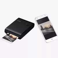Canon SELPHY SQUARE QX10 mobiler WLAN-Farbfotodrucker, Premium-Kit, Schwarz Ansicht von links mit Ausdruck und Handy auf der rechten Seite