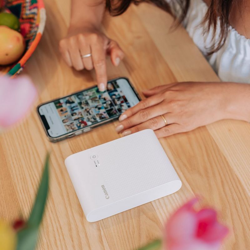 Canon SELPHY SQUARE QX10 Portable Colour Photo Wireless Printer Premium Kit, White Hand operating the phone with Product