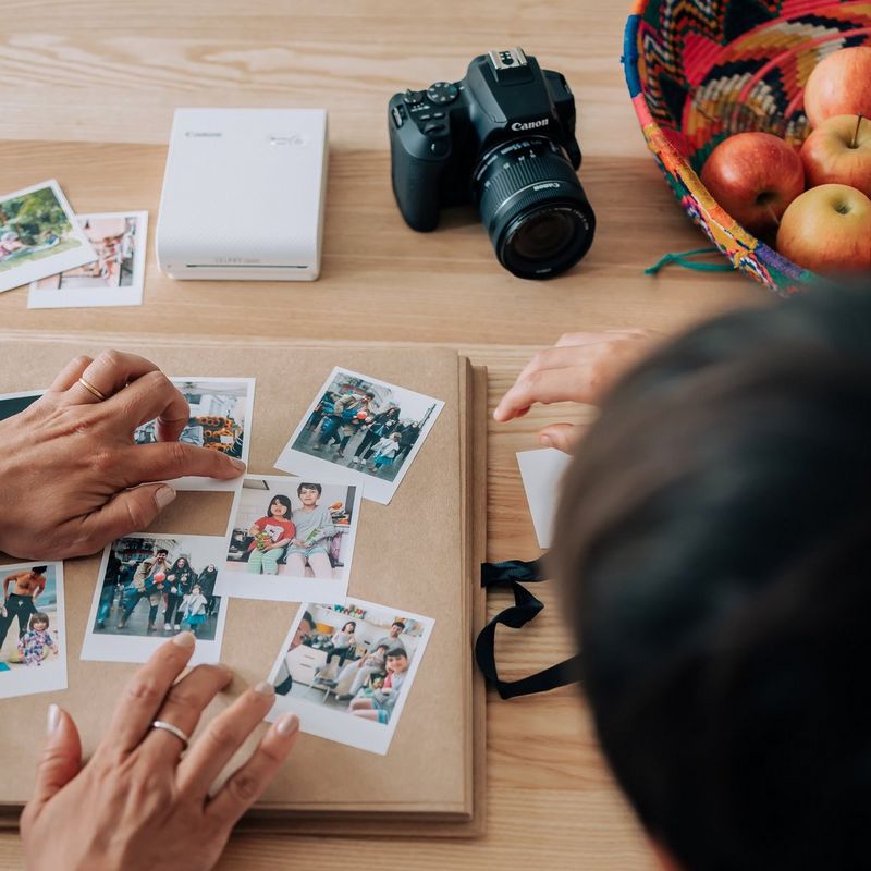 Canon SELPHY SQUARE QX10 Portable Colour Photo Wireless Printer Premium Kit, White Hands sticking pictures on Album