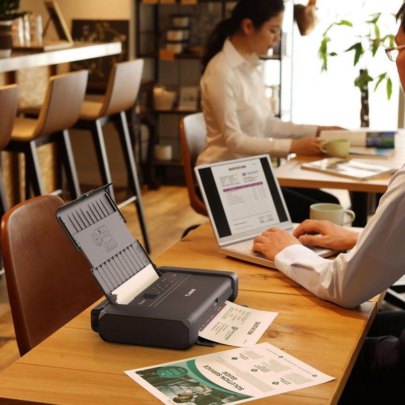 Canon PIXMA TR150 Portable Inkjet Printer with Battery Product Front View With A Person Printing From a Laptop