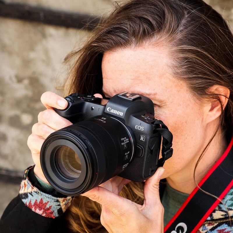 Canon RF 85mm F2 Macro IS STM Objektiv Eine Frau, die eine Kamera vor ihr Gesicht hält