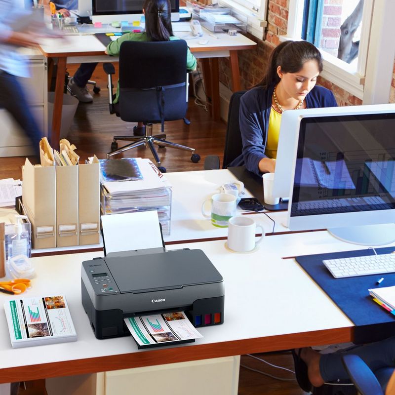 Canon PIXMA G3420 Wireless Colour 3-in-1 Refillable MegaTank Printer Kept On A Office Table Beside A Desktop With Paper Tray Out And Paper Support