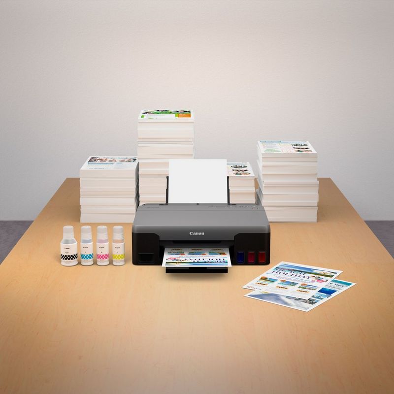 Canon PIXMA G1420 Colour Refillable MegaTank Printer Kept On A Table Along With Printed Paper And Inks