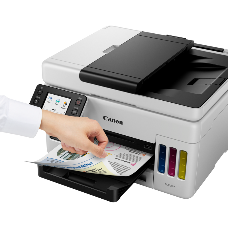 Canon MAXIFY GX6050 Wireless 3-in-1 Refillable MegaTank Inkjet Printer Produkt Sett skrått forfra med en person som fjerner bildet fra papirskuffen
