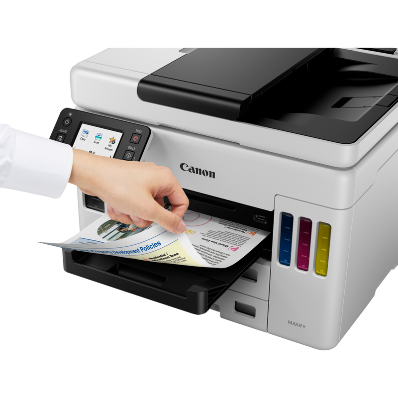 Canon MAXIFY GX7040 Wireless Colour All-in-one Refillable MegaTank Inkjet Printer Product Front Slant View With A Person Removing the Photo From The Paper Tray Out