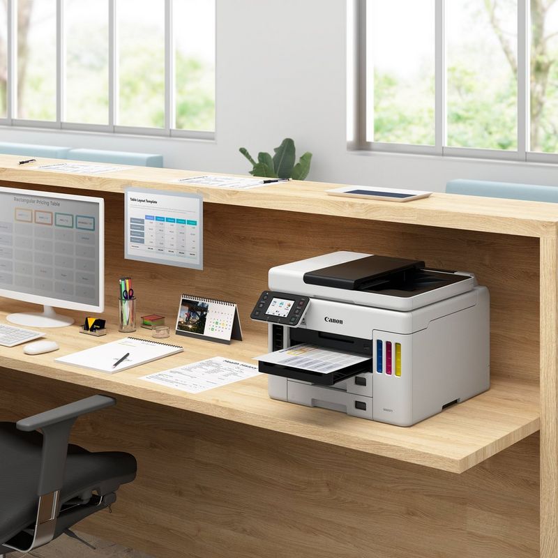 Canon MAXIFY GX7040 Wireless Colour All-in-one Refillable MegaTank Inkjet Printer Kept On A Office Table Beside A Desktop With Paper Tray Out