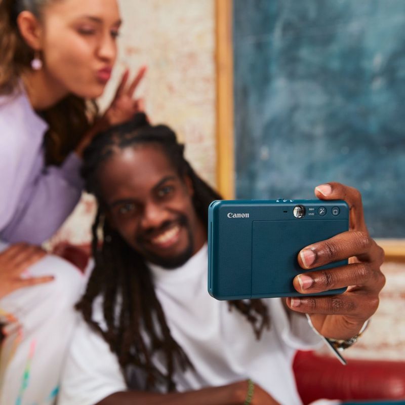 Canon Zoemini S2 Instant Camera Colour Photo Printer, Teal + Diary + Pouch Couple clicking a selfie with blackboard in the background