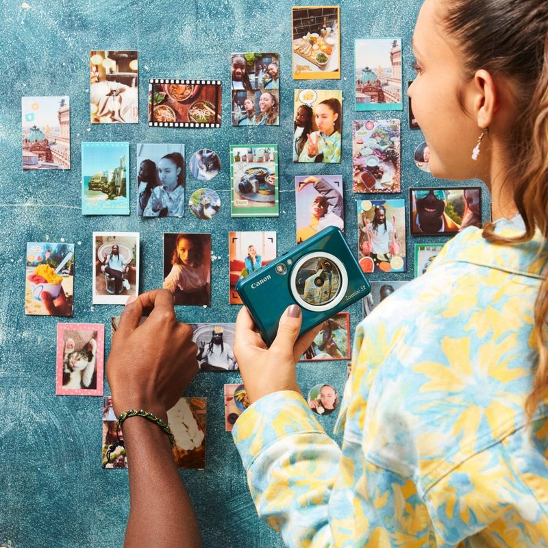 Canon Zoemini S2 Instant Camera Colour Photo Printer, Teal + Diary + Pouch Couple sorting printouts on a wall