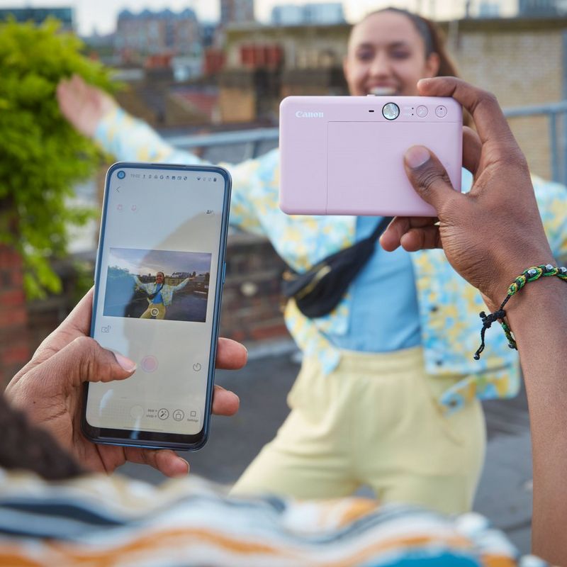 Canon Zoemini S2 Instant Camera Colour Photo Printer, Rose Gold + Diary + Pouch person clicking a photo with a mobile in his hand