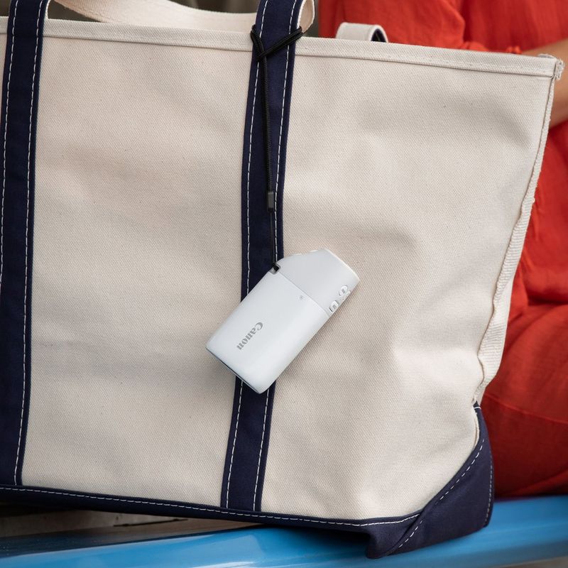 Canon PowerShot ZOOM Telephoto Monocular Compact Camera Essential Kit, Black Camera attached to a hand bag