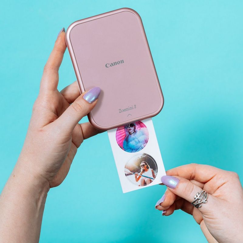 Canon ZINK™ 1.3” Pre-Cut Circle Sticker Pack, 20 sheets Product In Use On A Table Next To A Canon Zoemini Printer and A Smartphone