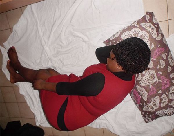 A woman, sleeping on sheets and a pillow, on the floor.