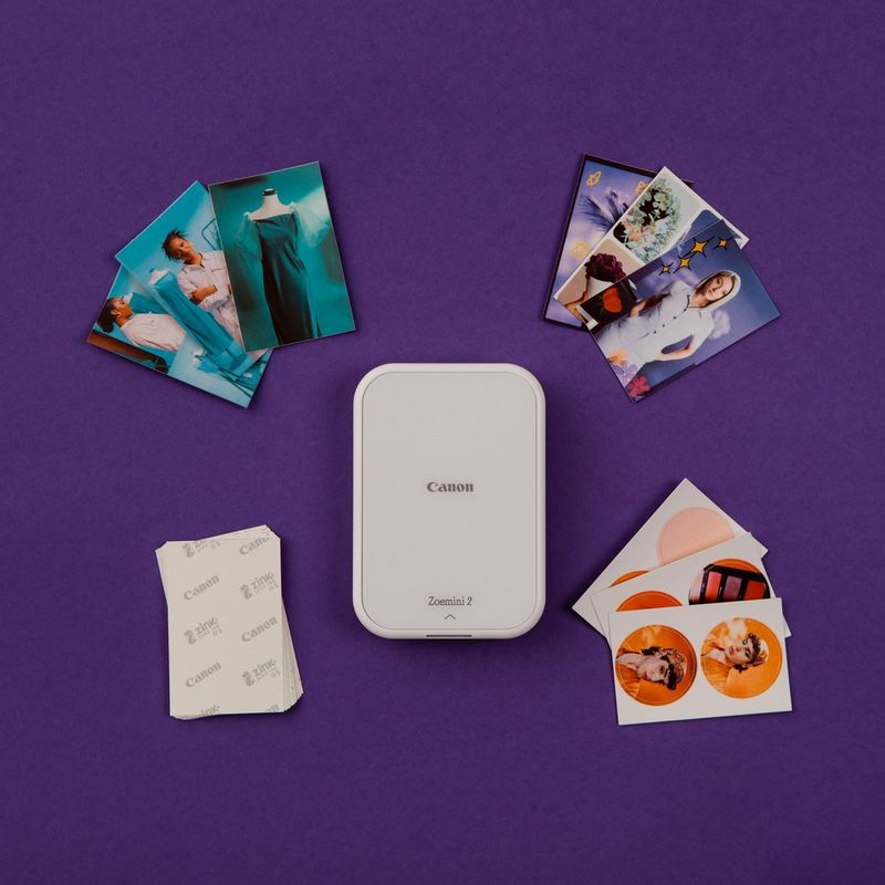 Canon Zoemini 2 mobiler Mini-Fotodrucker, Weiß Produkt zwischen einem Stapel verschiedener Fotos