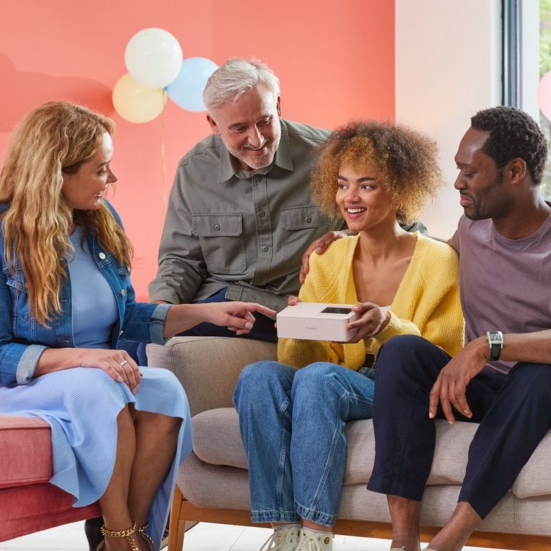 Neljä henkilöä istuu ja pitää tuotetta käsissään