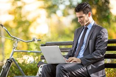 a man sitting on a bench working on laptop