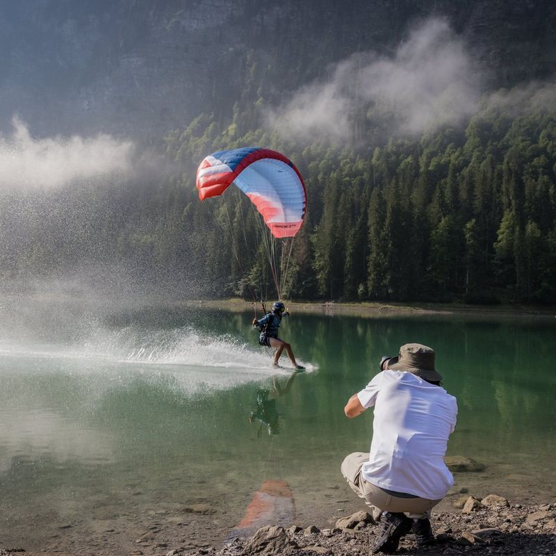 Canon EOS R6 Mark II spiegellose Kamera, Schwarz + Rucksack + SD-Karte+ Ersatzakku Ein Mann, der an einem See Fotos von einem Paragleiter aufnimmt