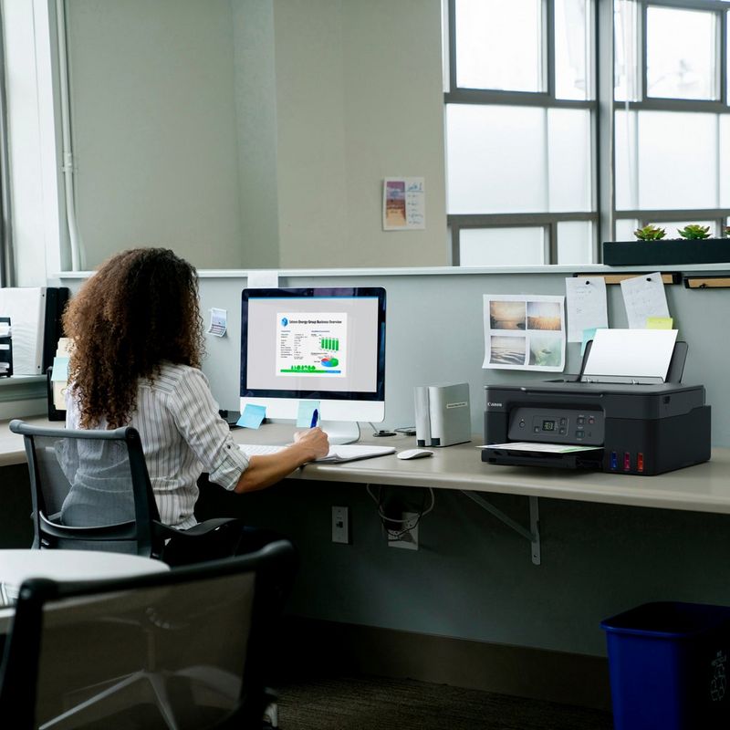 Canon PIXMA G2470 Colour 3-in-1 Refillable MegaTank Printer Product kept on Office Desk with a women working on a computer