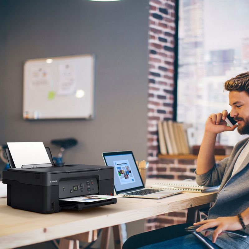 Canon PIXMA G2470 Colour 3-in-1 Refillable MegaTank Printer Product kept on a Office Desk with a Man speaking on a phone