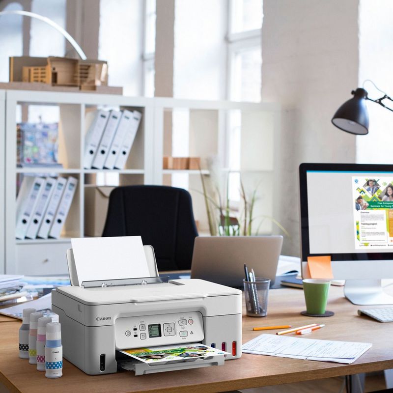 Canon PIXMA G3571 Wireless Colour 3-in-1 Refillable MegaTank Printer, White Product kept on a Office Desk with ink bottles