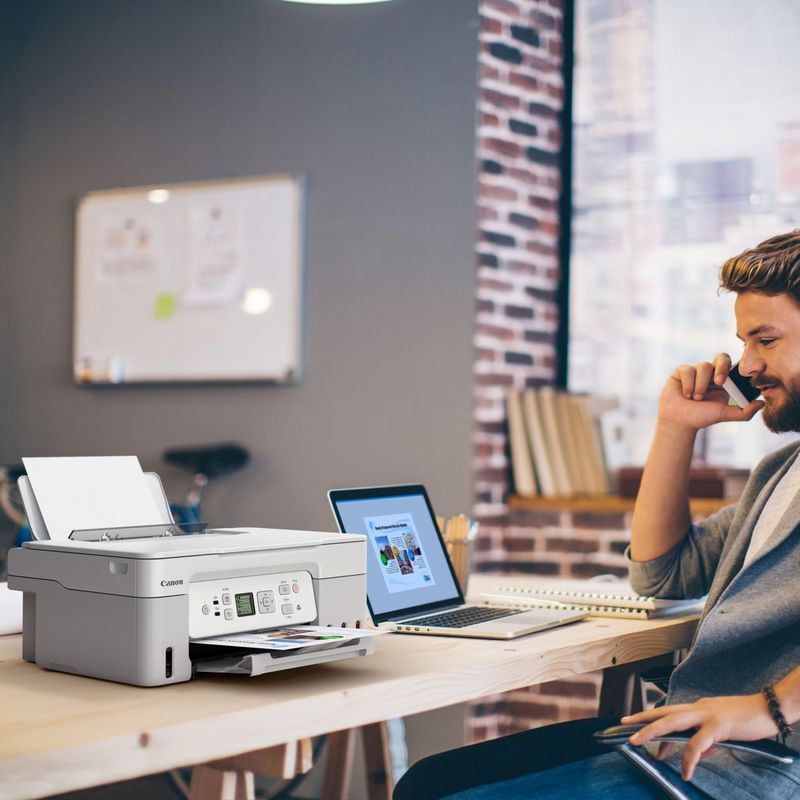 Canon PIXMA G3571 Wireless Colour 3-in-1 Refillable MegaTank Printer, White Product kept on a Office Desk with a Man speaking on a phone