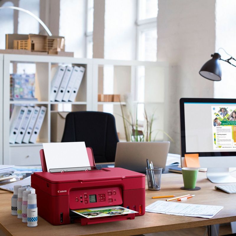 Canon PIXMA G3572 Wireless Colour 3-in-1 Refillable MegaTank Printer, Red Product kept on a Office Desk with ink bottles