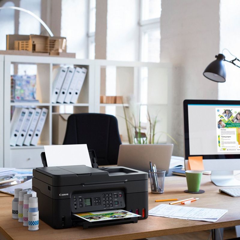 Canon PIXMA G4570: impresora multifunción inalámbrica MegaTank de inyección de tinta color con depósitos de tinta rellenables Producto en el escritorio de una oficina junto a botellas de tinta