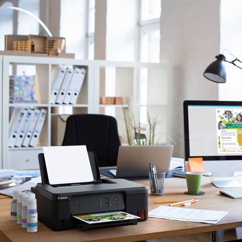 Imprimante MegaTank rechargeable couleur Canon PIXMA G1530 Produit posé sur un bureau avec des bouteilles d'encre