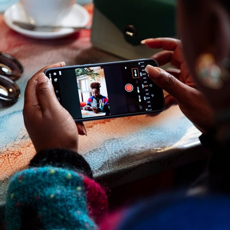 Canon EOS R50 Mirrorless Camera Body, Black Person holding a phone