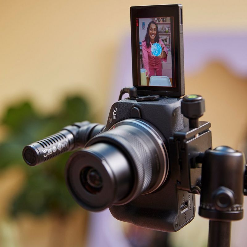 Appareil photo hybride Canon EOS R50 noir - Kit pour vlogueur Produit fixé sur un trépied avec microphone et écran ouvert