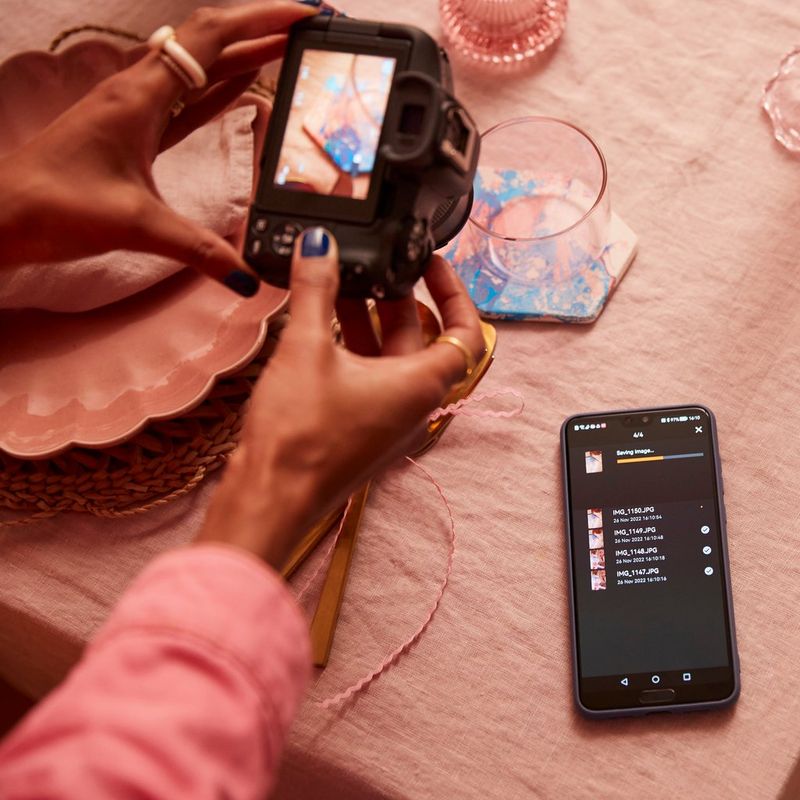 Canon EOS R50 Mirrorless Camera, Black + RF-S 18-45mm F4.5-6.3 IS STM Lens + Backpack + SD Card + Spare Battery Women photographing a glass with a phone besides it