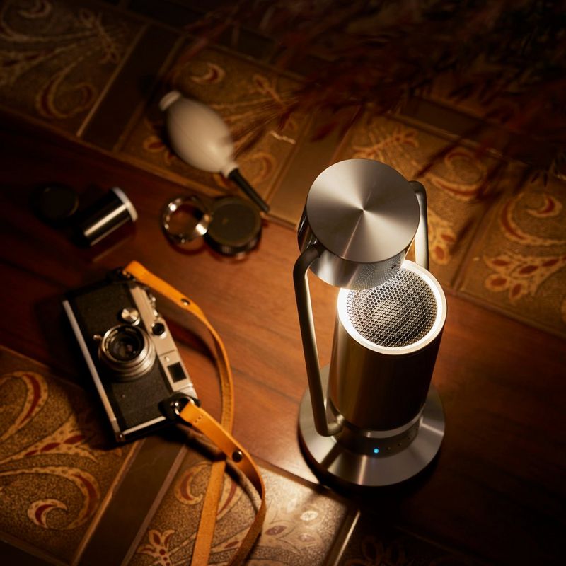 Canon Leuchte & Lautsprecher ML-A: drahtlose Bluetooth Lautsprecher Lampe aus Aluminium - Silber Produkt mit gekipptem Arm und eingeschalteter Lampe auf einem Tisch