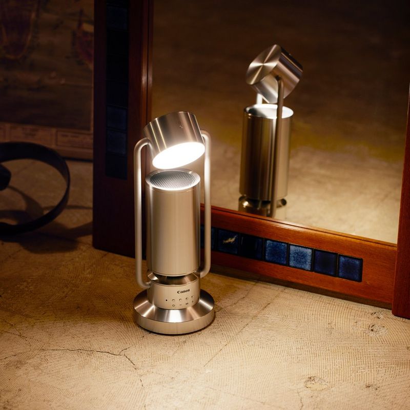 Canon Leuchte & Lautsprecher ML-A: drahtlose Bluetooth Lautsprecher Lampe aus Aluminium - Silber Produkt mit gekipptem Arm und eingeschalteter Lampe auf einem Tisch