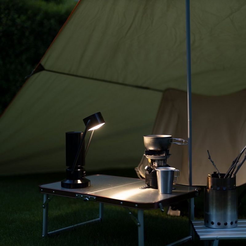 Lámpara Bluetooth inalámbrica de aluminio Canon Luz & Altavoz ML-A - negro Producto con el brazo inclinado en una tienda de campaña con la lámpara encendida