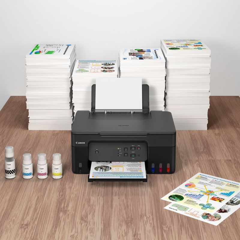 Canon PIXMA G2430 Colour 3-in-1 Refillable MegaTank Printer inks and printouts kept on a table