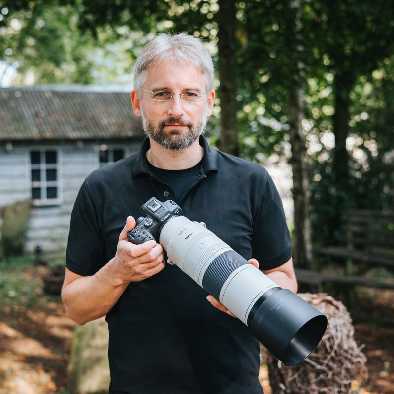 Canon RF 200-800mm F6.3-9 IS USM -objektiivi Henkilö pitelee tuotetta liitettynä kameraan vastavalosuojan kanssa