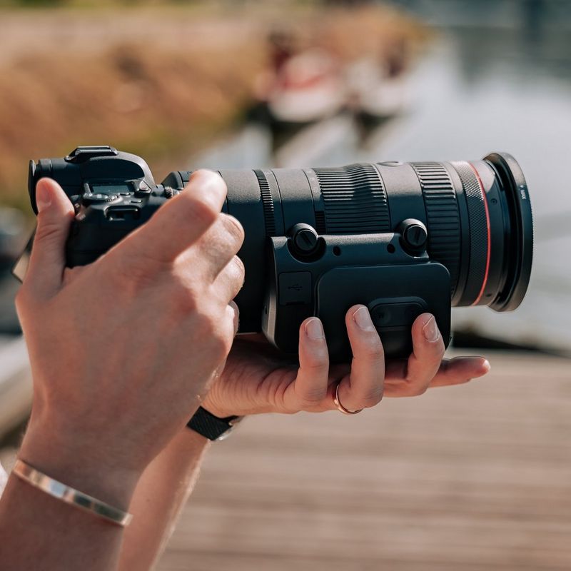 Adaptador de zoom motorizado Canon PZ-E2 Hombre haciendo una foto mientras el producto está acoplado a un objetivo