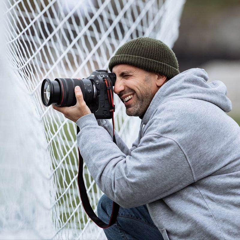 Canon EOS R1 spiegelloses Kameragehäuse Mann, der ein Foto auf einem Fußballfeld knipst