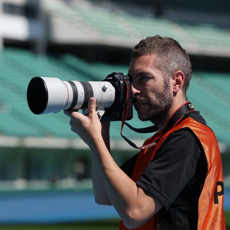 Canon RF 70-200mm F2.8L IS USM Z Lens, White  Man clicking a photo on a sports field