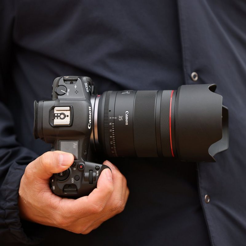 Objectif Canon RF 35mm F1.4L VCM Homme tenant un appareil photo sur lequel est fixé un objectif