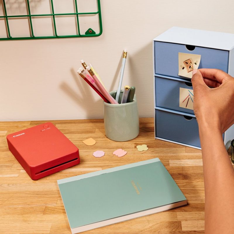 Canon SELPHY QX20 Portable Colour Photo Wireless Printer, Terracotta Red Product with Printed photos sticking on Cupboard