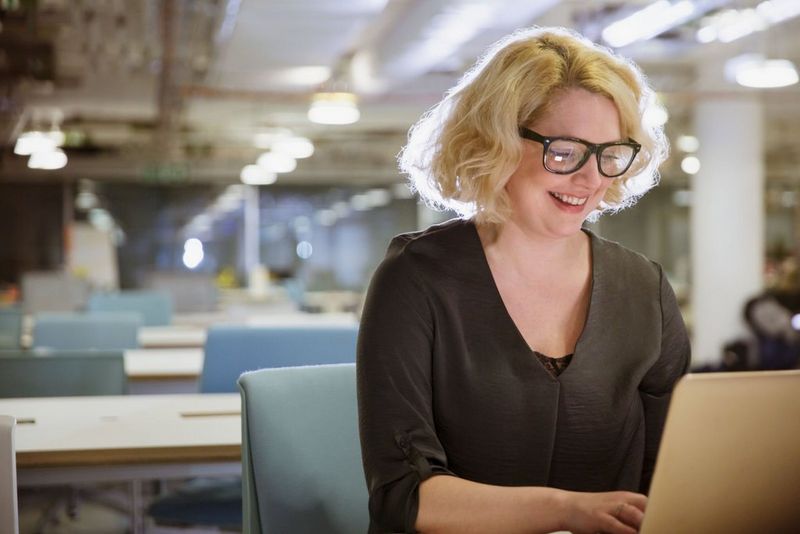 a woman smiling at her laptop