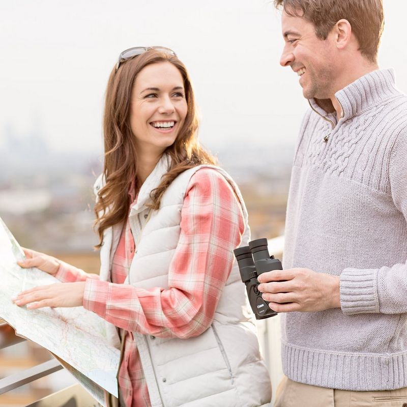 Canon 10x30 IS II Binoculars Woman Smiling at a Man Whilst Holding a Map and Man Smiling Back Whilst Holding Binoculars in his Hands