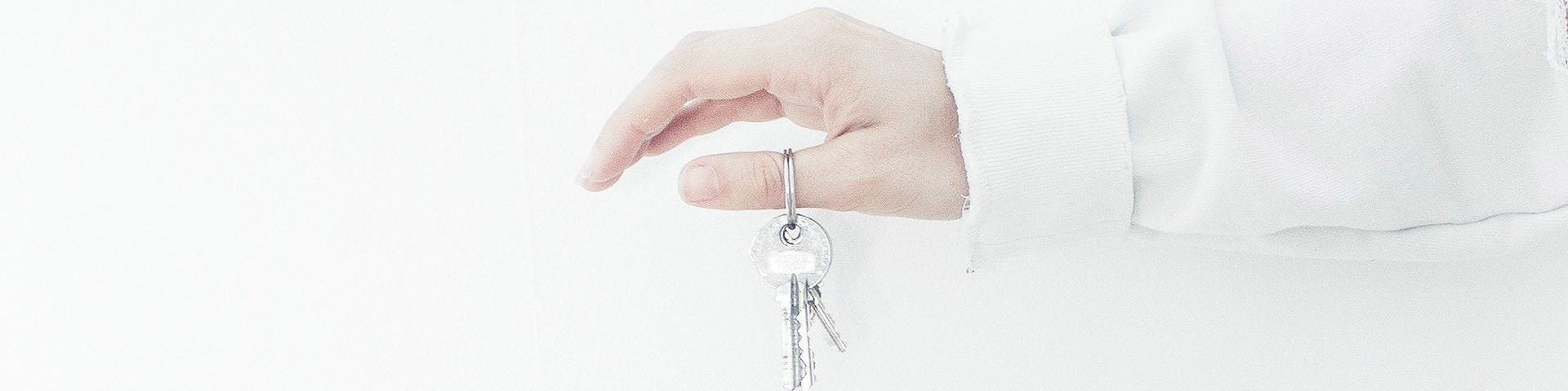 An outstretched arm and hand, dangling a set of keys from the thumb.