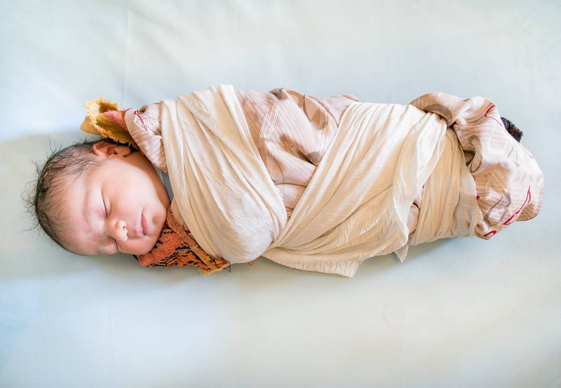 A newborn infant tightly swaddled in subtly patterned cloth. Photograph by Lieve Blancquaert.