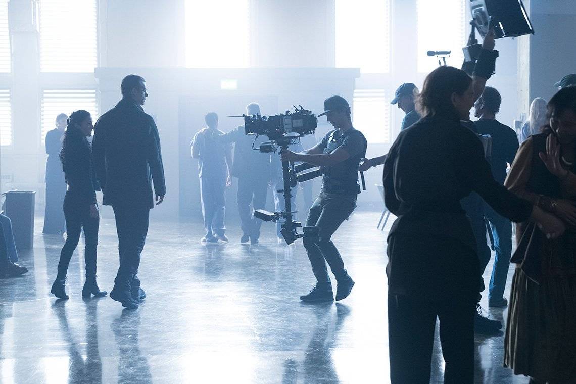 Two actors walk in a light-filled room, being filmed for Altered Carbon.