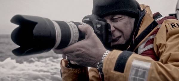 Photographer Clive Booth holds a Canon EOS 5DS with a long Canon lens.