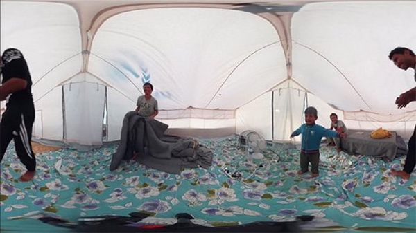 A still image from a 360-degree VR camera shows the inside of a tent with a turquoise floral rug, teenagers and a young child.