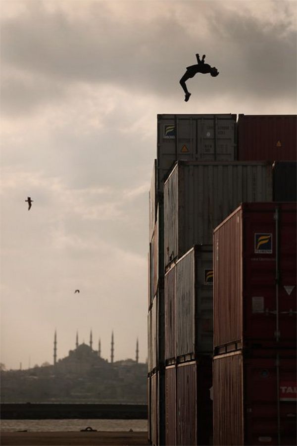  A man does a backflip on a stack of shipping containers as the sun sets on the minarets of Istanbul.